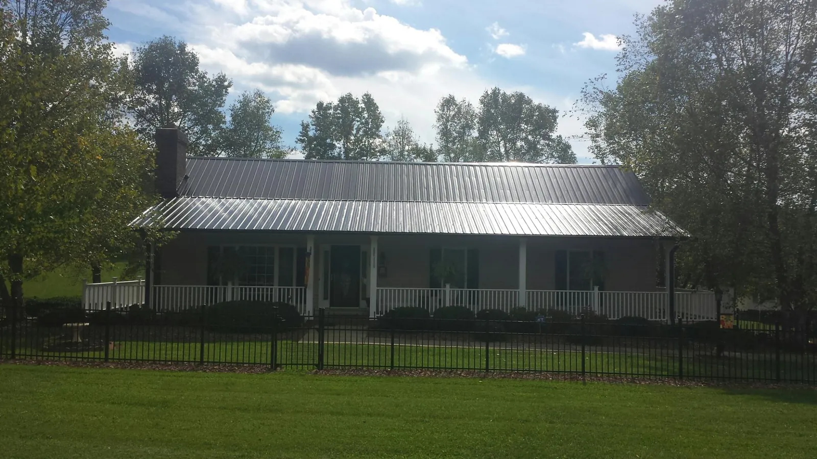 Gray metal roof on a brick ranch with a full width front porch — Gutter Guard Installation work by our crew in Dundee
